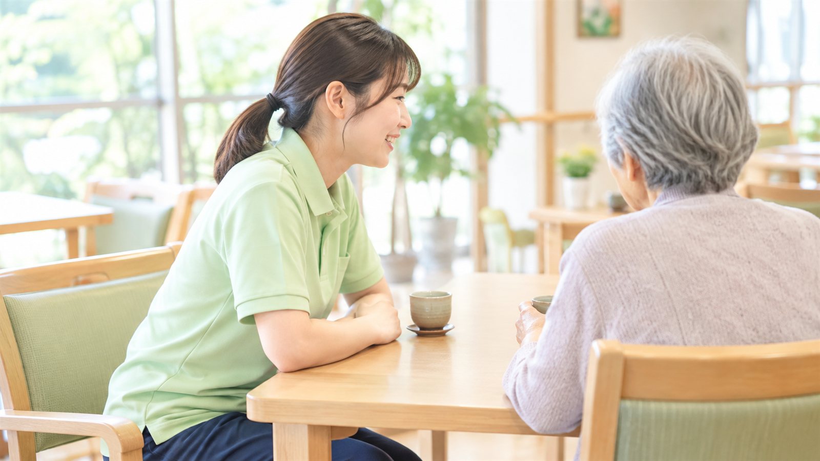明るいフロアで、スタッフが高齢の方とテーブルをはさんで話している様子